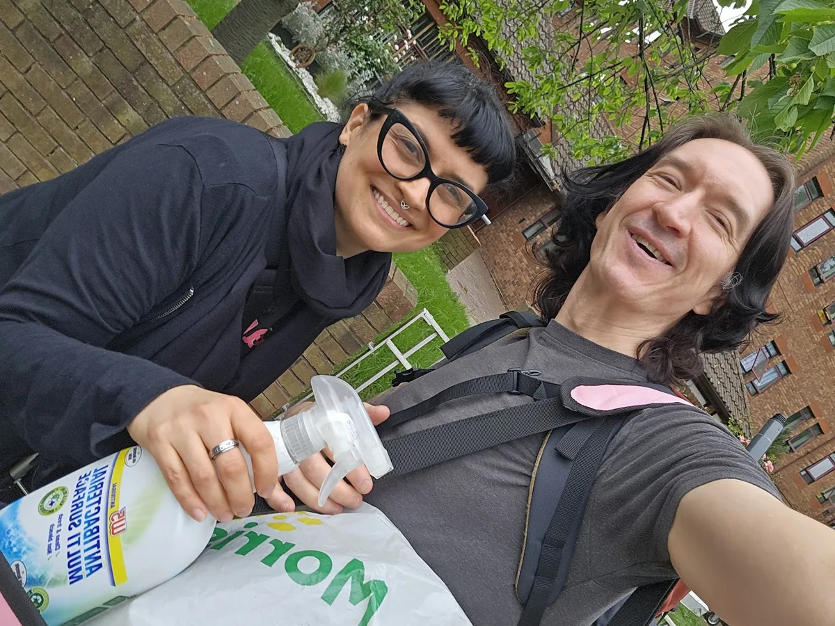 Kari and David smiling in a selfie outdoors, Kari holding a bottle of cleaning spray